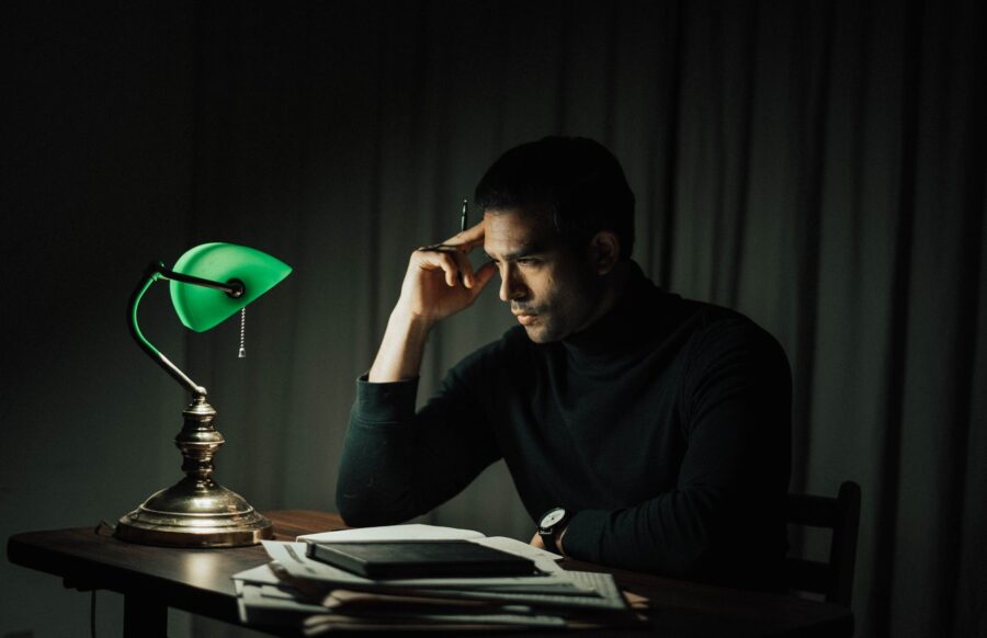 wistful man with documents at table in dark room